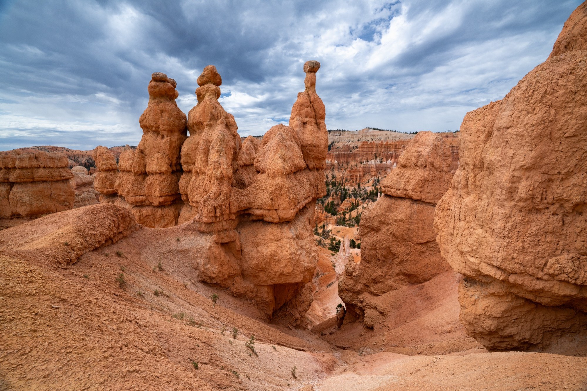 Orange sandstone towers and hoodoos beneath a cloud-filled sky