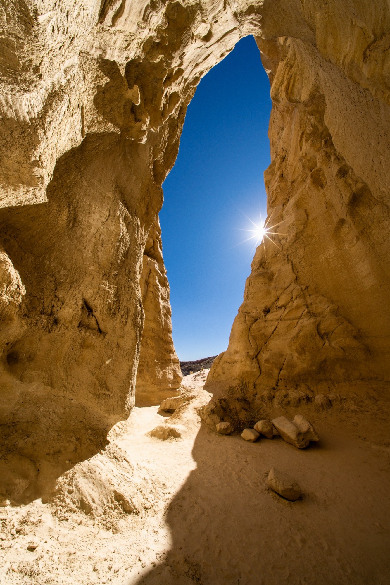 A narrow opening in golden rock framing blue sky
